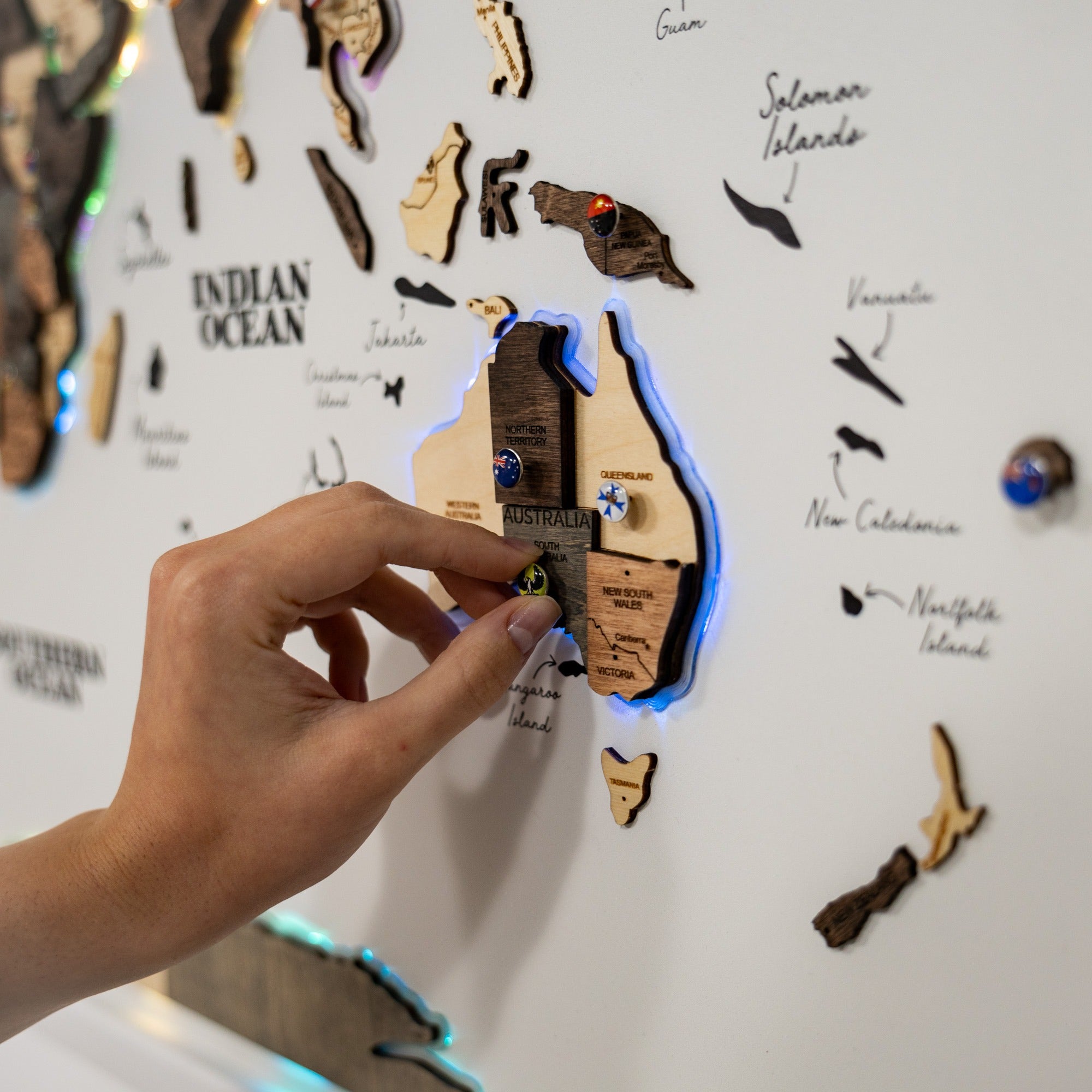 Hand interacting with a wooden map of Australia on a world map background