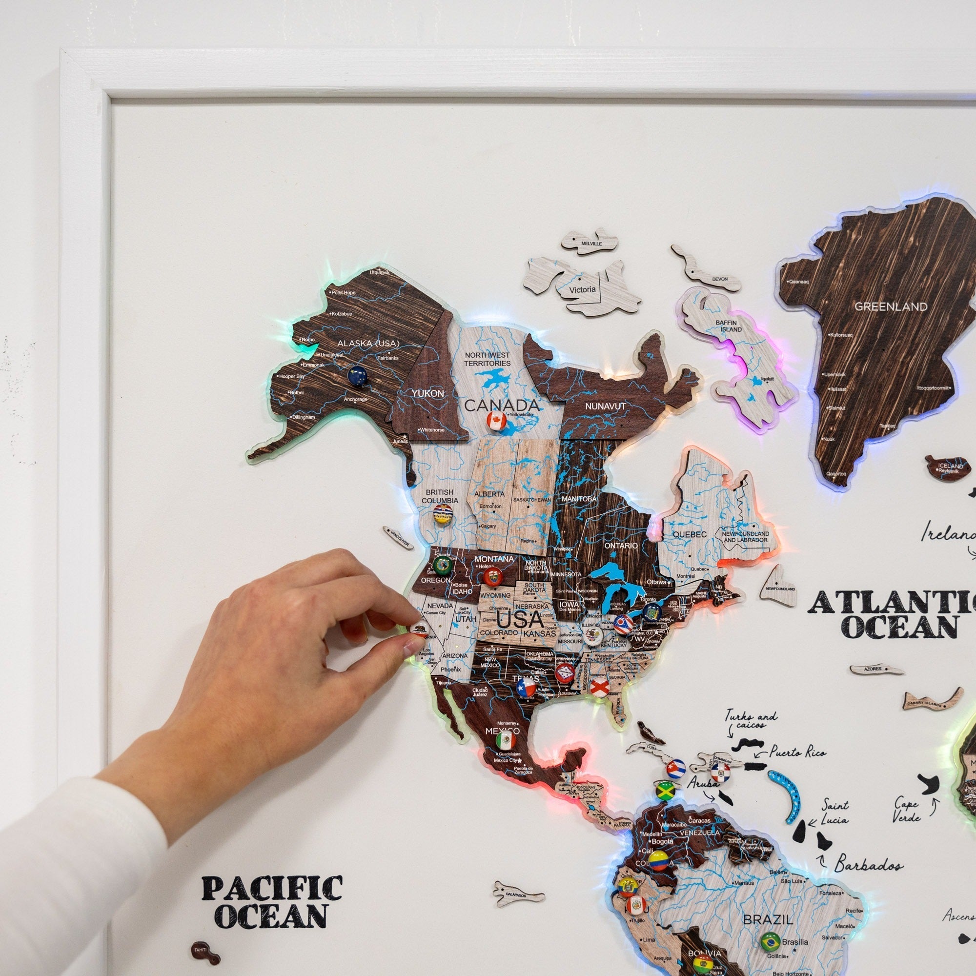 Wooden world map with illuminated countries, hand placing a country piece.