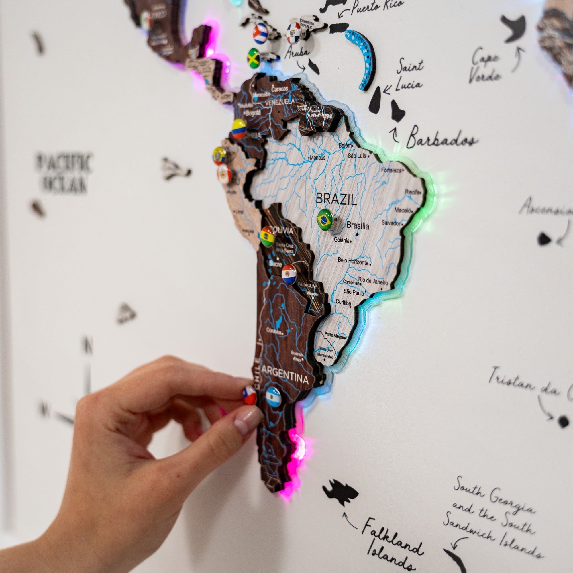 Map of South America with country flags and a hand interacting with it on a white background.