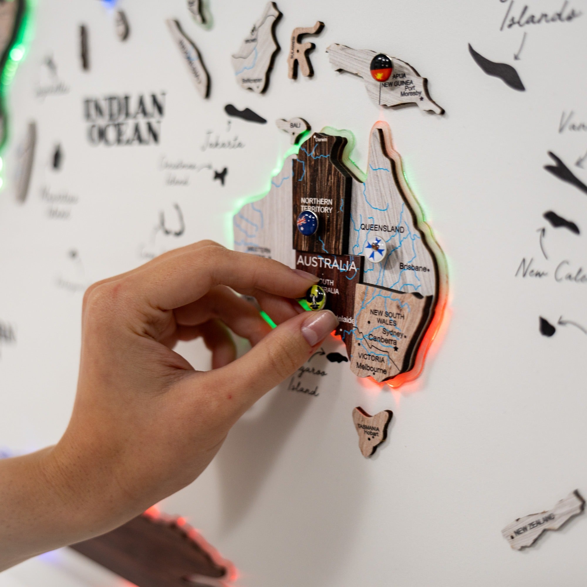 Hand interacting with a map of Australia on a light-up board with glowing edges.