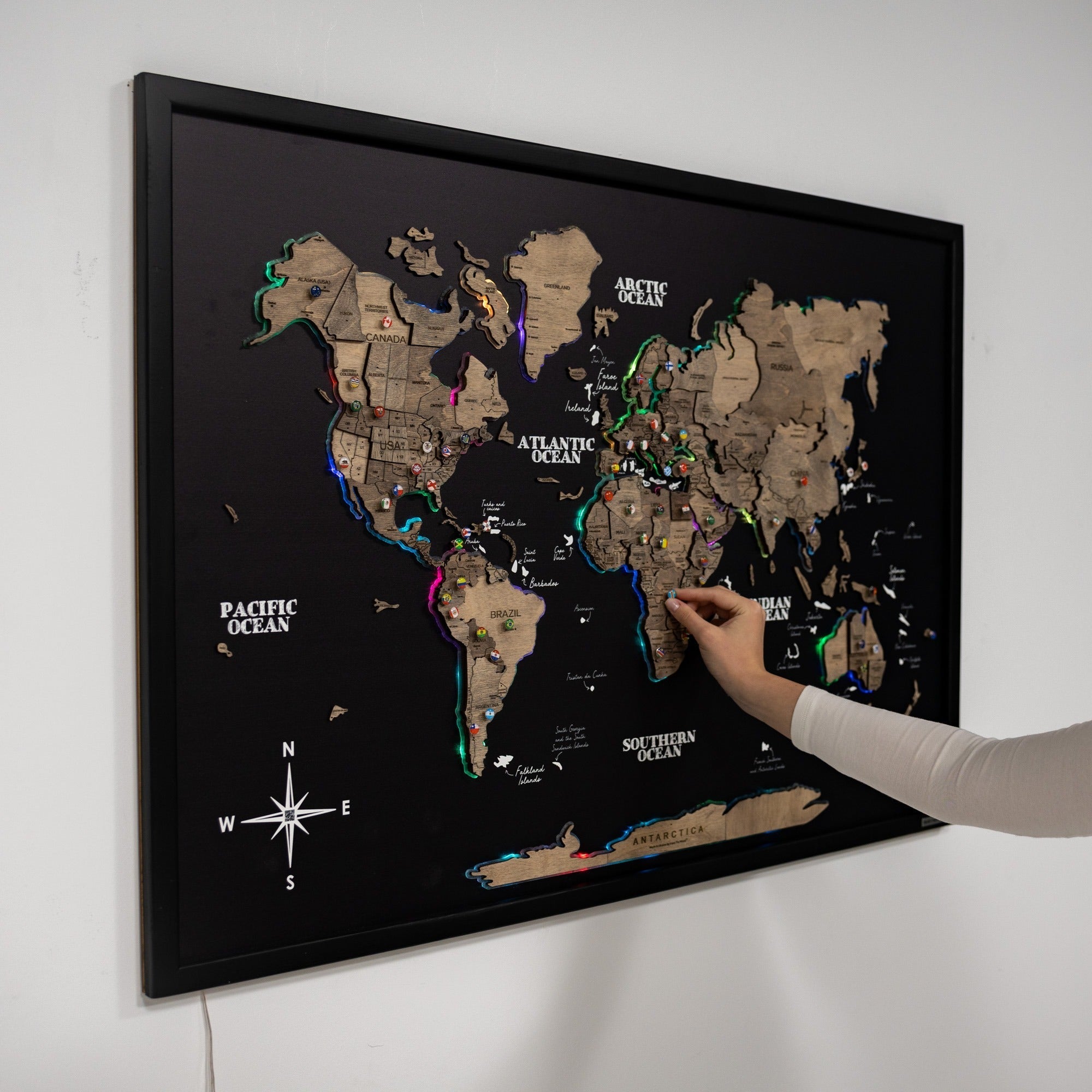 World map with LED lights on a black background, being interacted with by a hand.