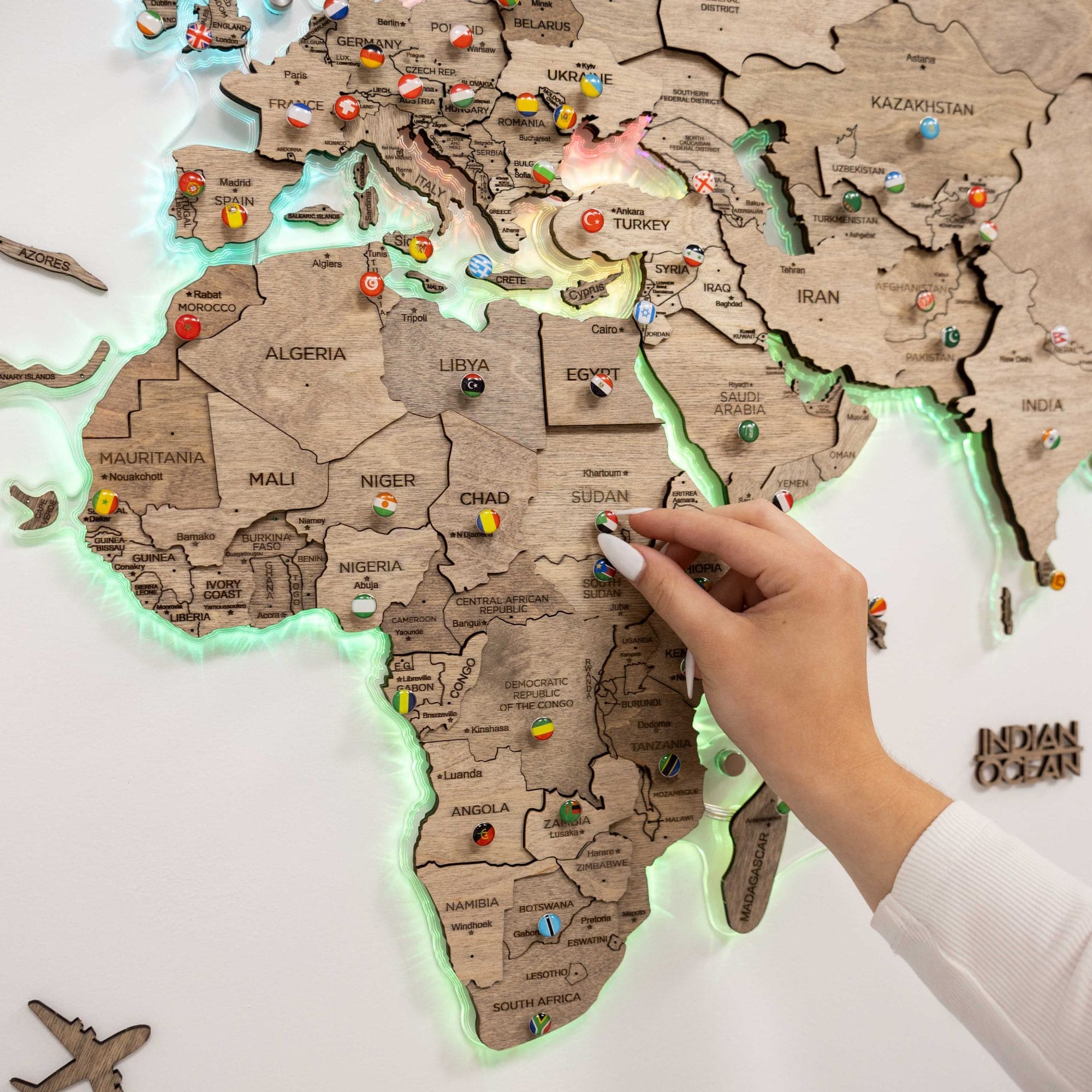 World map with pins marking locations, hand pointing to a specific area