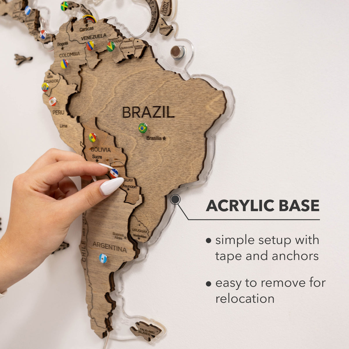 Wooden map of South America with acrylic base, hand pointing to Brazil.