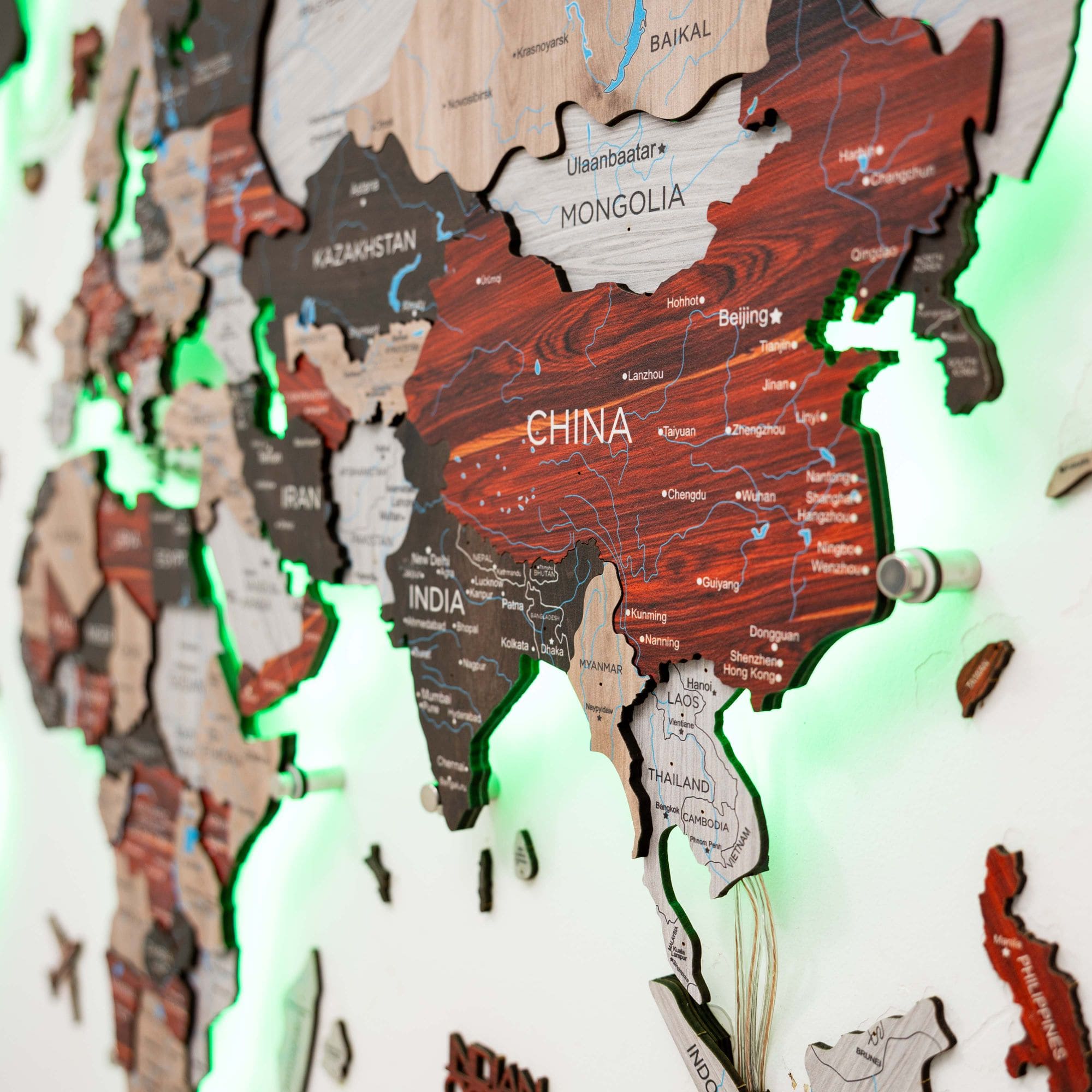 Wooden map of Asia with a focus on China, illuminated by green light.