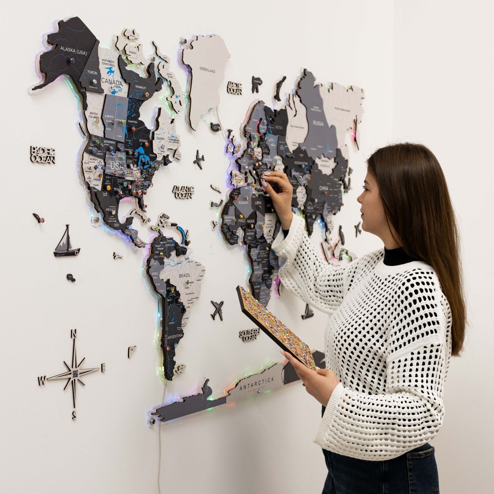 Woman interacting with a world map puzzle on a wall