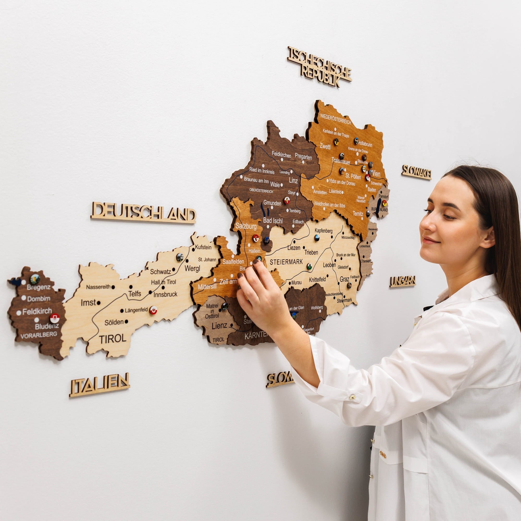 Woman interacting with a wooden map of Germany on a white wall
