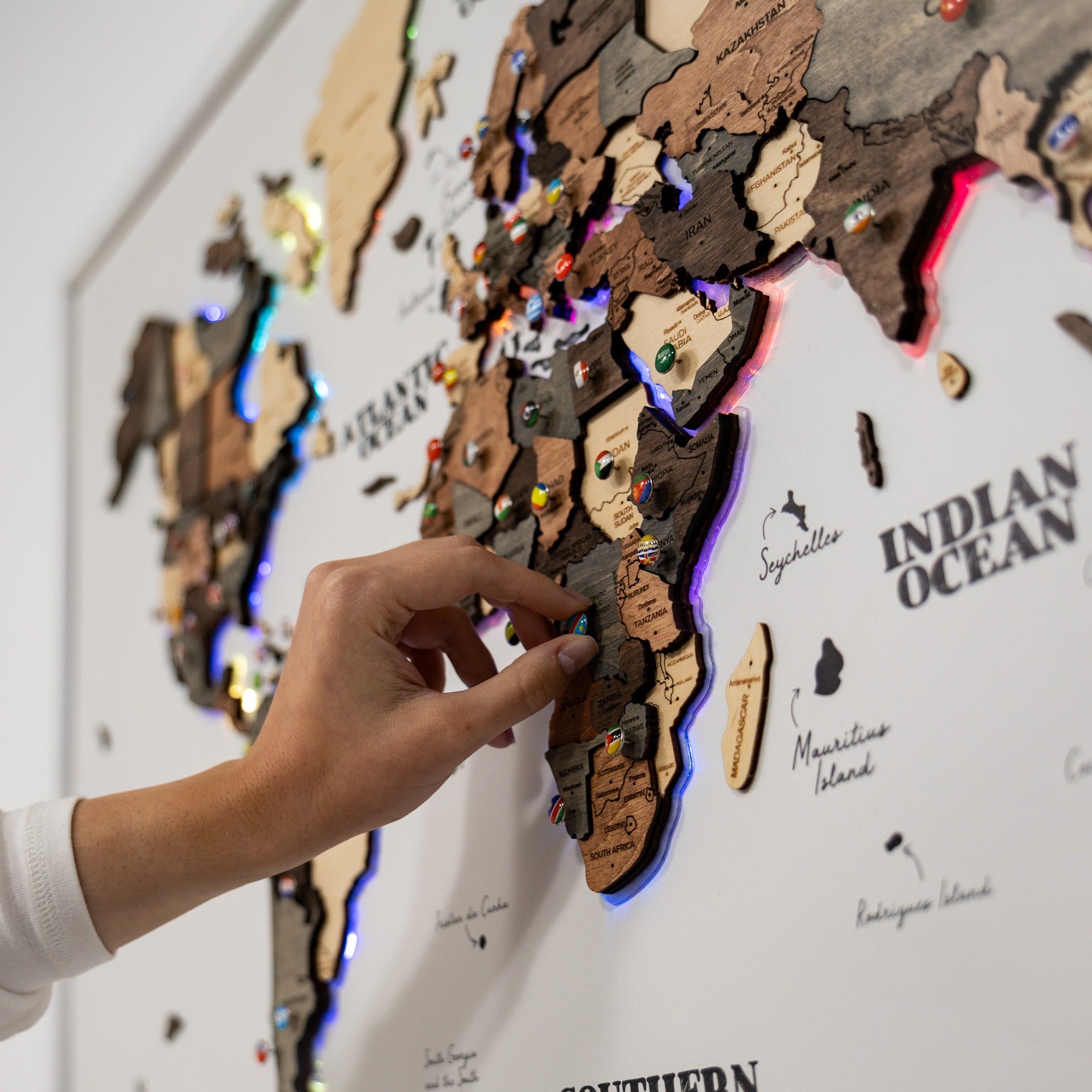 Hand placing a wooden puzzle piece on a world map with colorful lights.