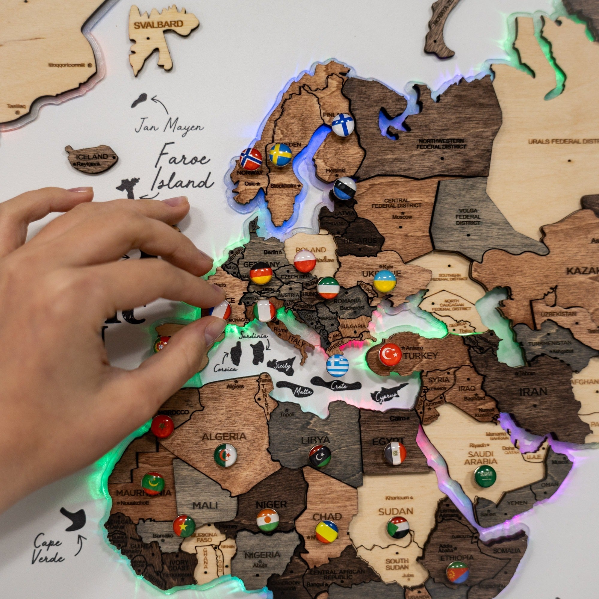 Wooden map of the world with glowing edges and a hand interacting with it.