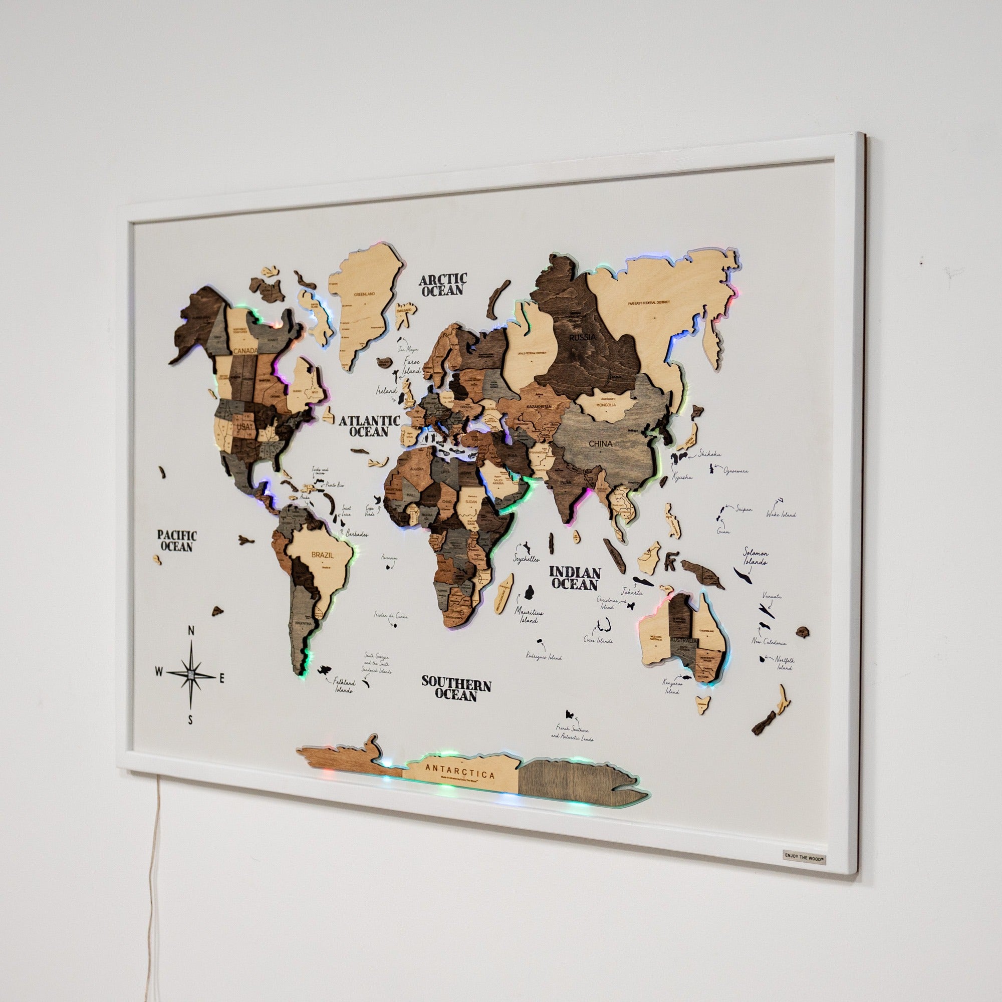 Wooden world map with LED lights on a white wall