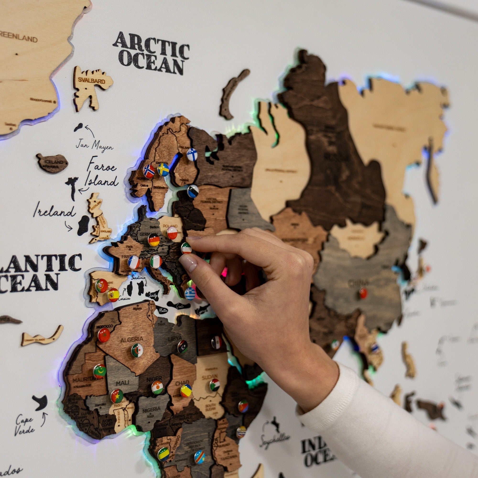 Hand placing a wooden puzzle piece on a map of Europe with country flags.