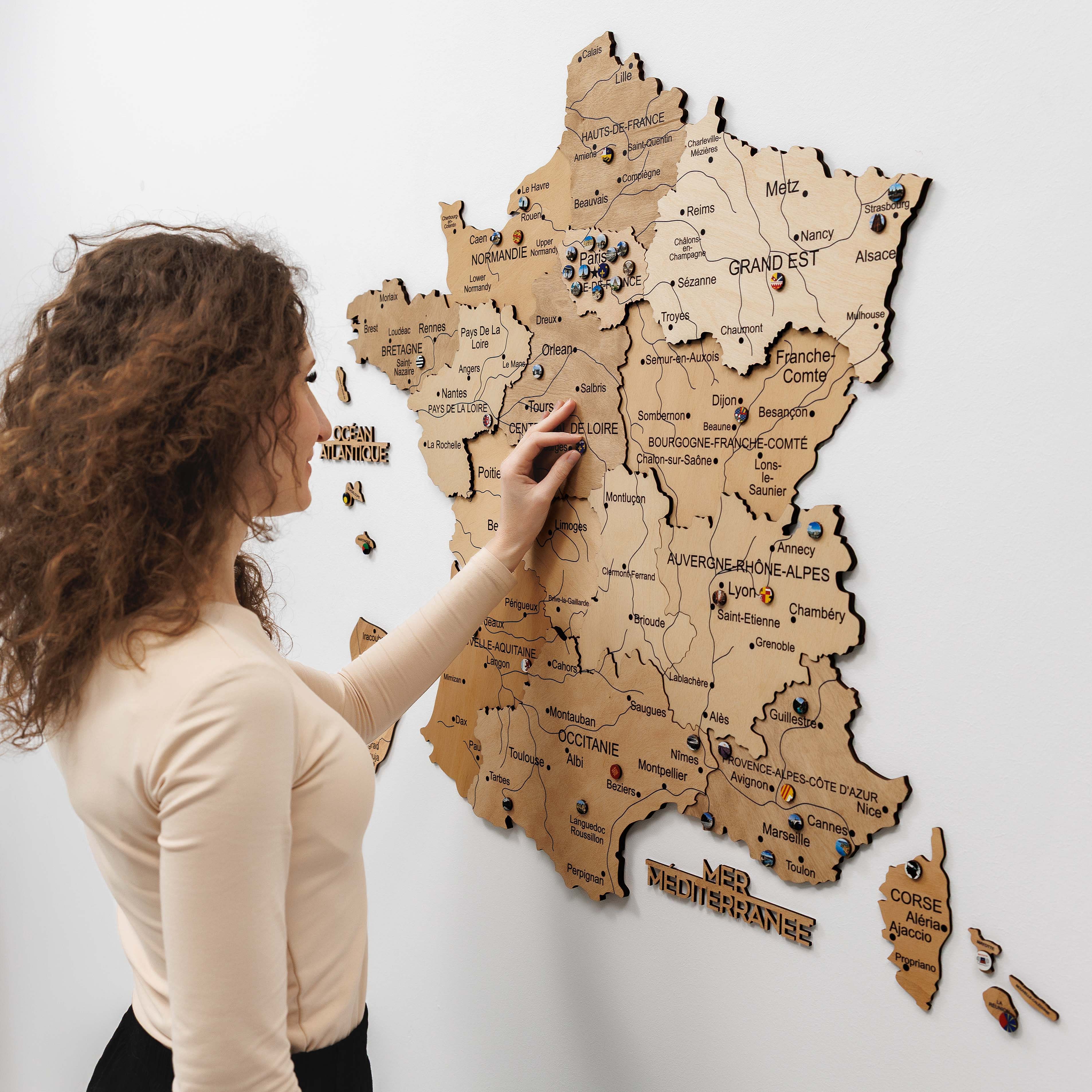 Woman interacting with a wooden map of France on a white wall