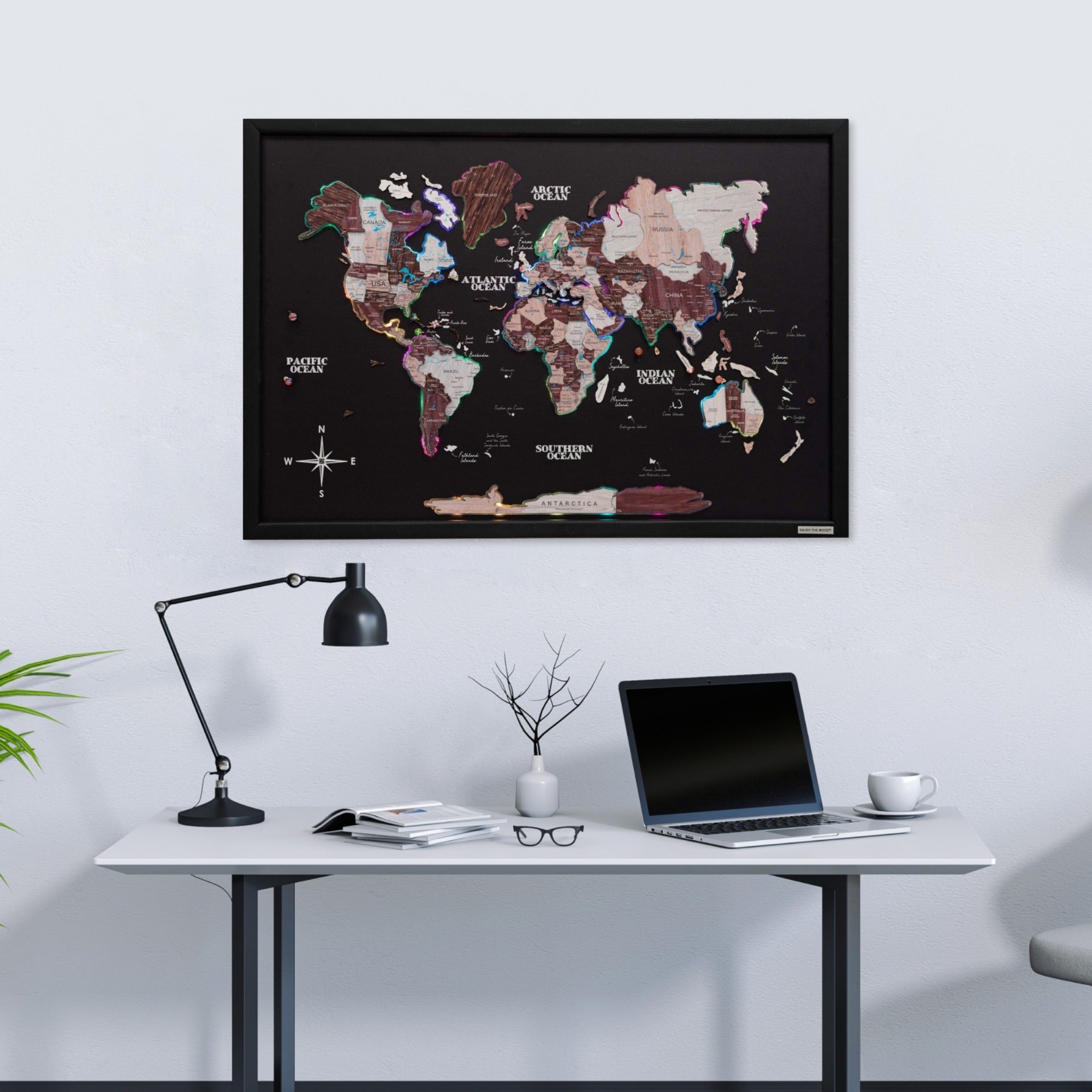 World map poster on a wall above a desk with a laptop and lamp.