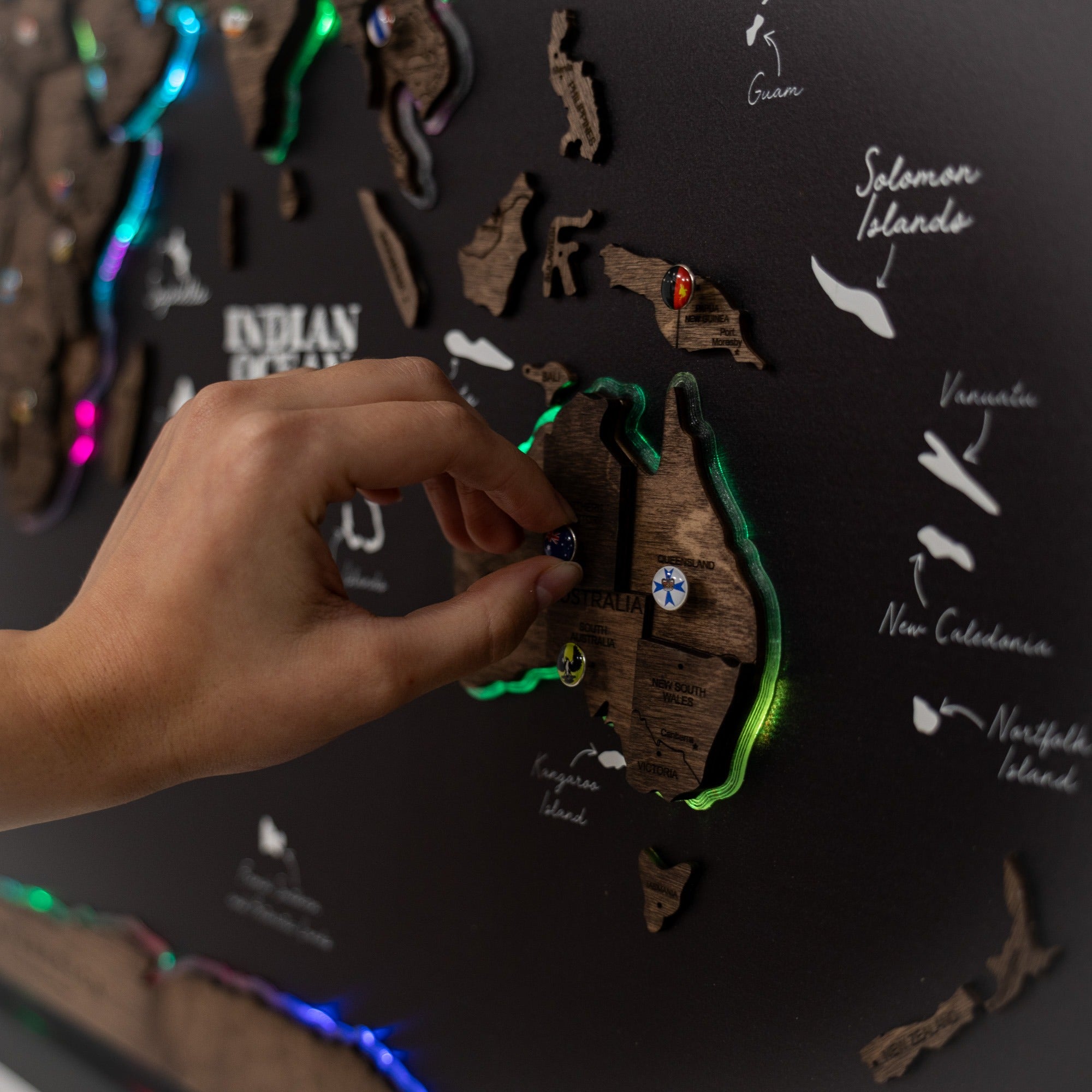 Hand interacting with a map of Oceania on a dark surface