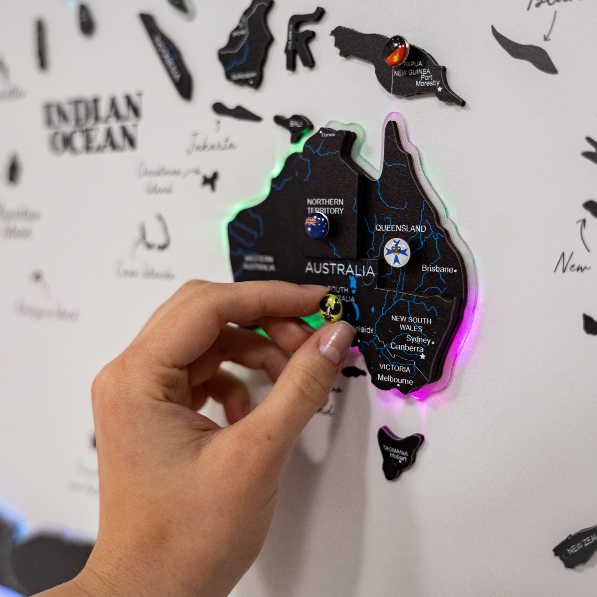 Hand holding a colorful Australia map against a white background with map illustrations.