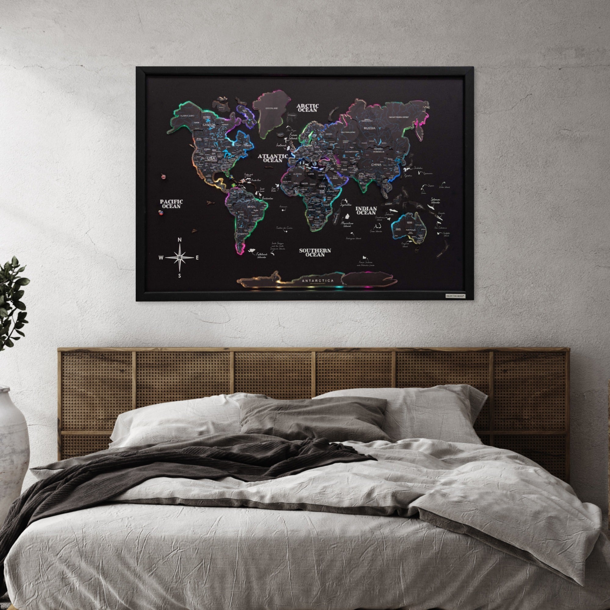 World map poster on a wall above a bed with wooden headboard