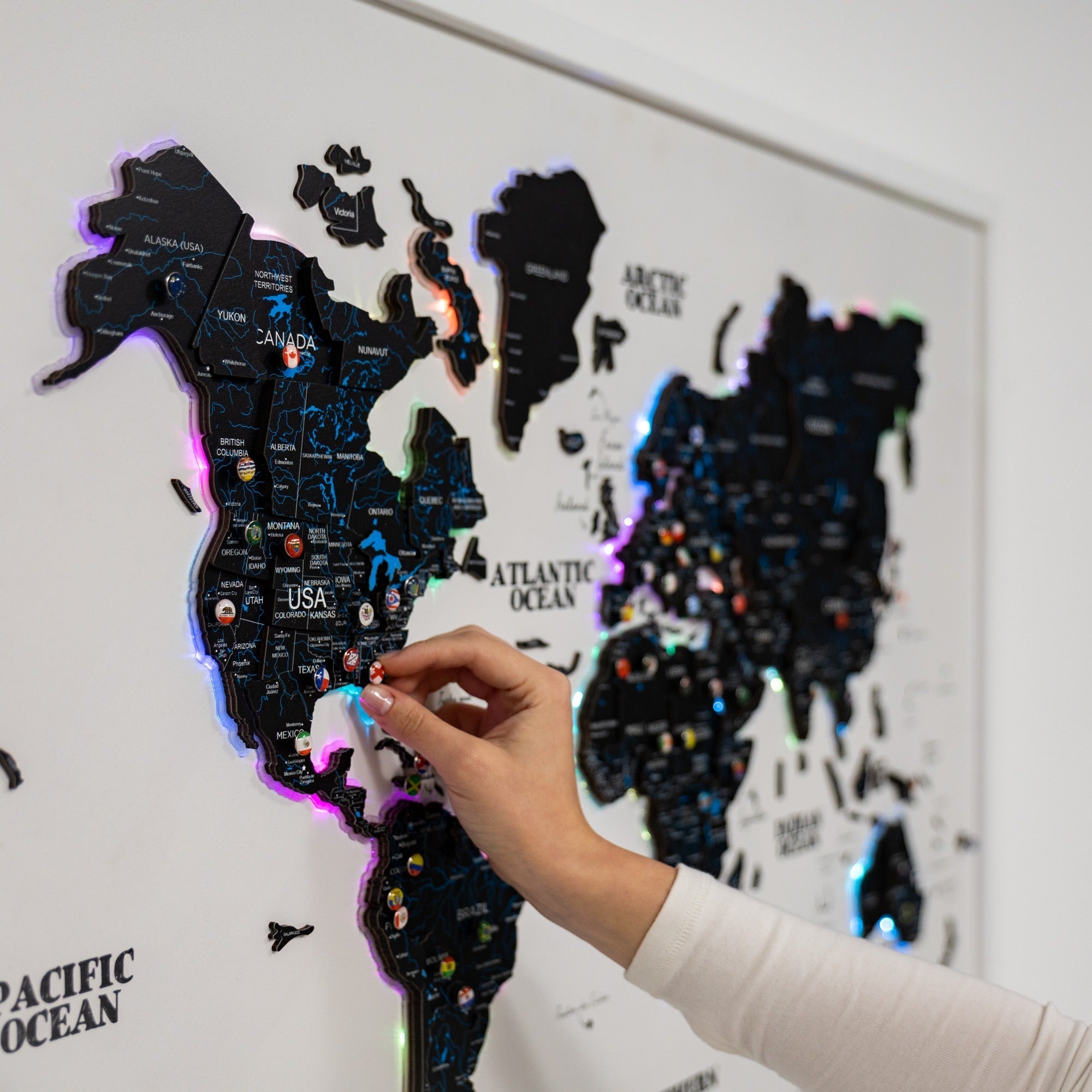Hand interacting with a illuminated world map on a wall