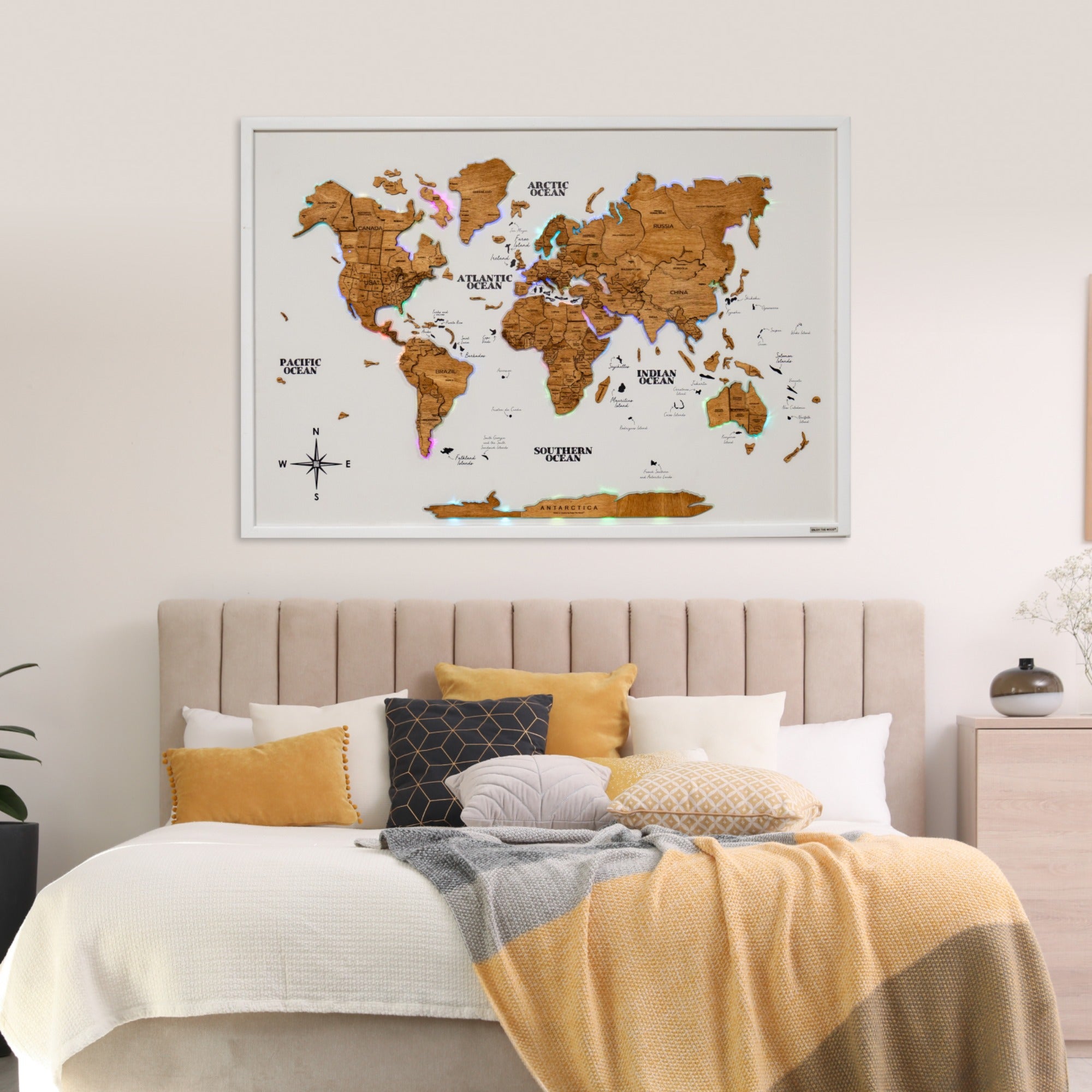 World map poster on a wall above a bed with decorative pillows and bedding.